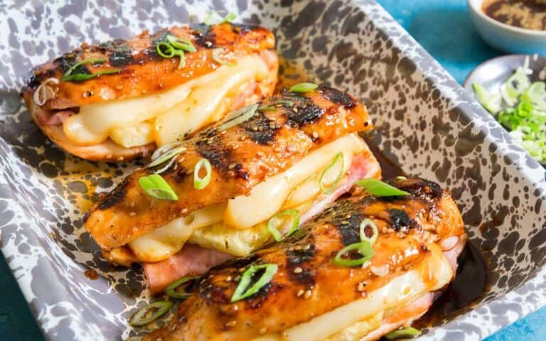 Grilled chicken stuffed with cheese, ham and pineapple in a baking dish.