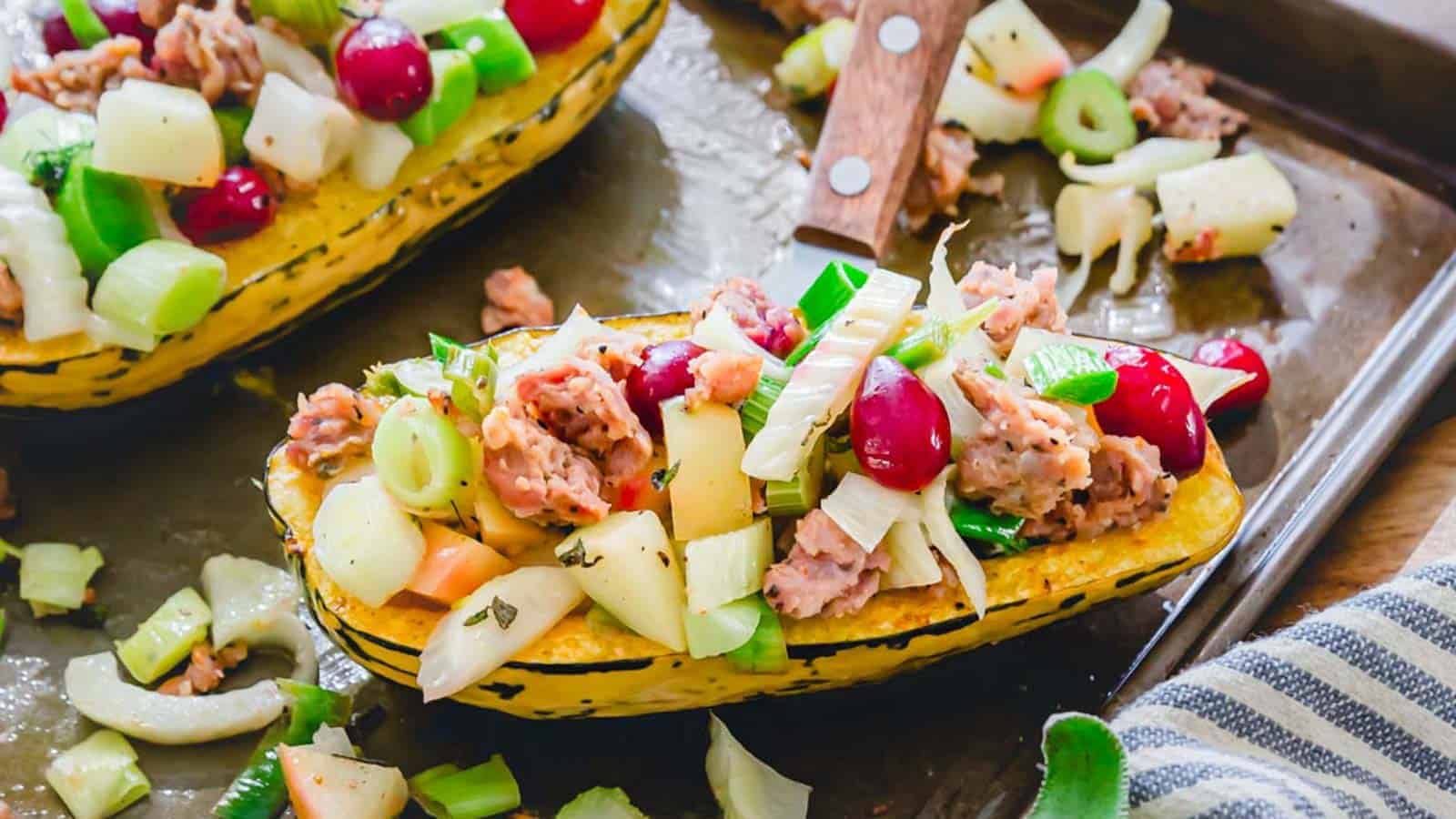 Stuffed delicata squash boats with cranberries and pork on a baking sheet.