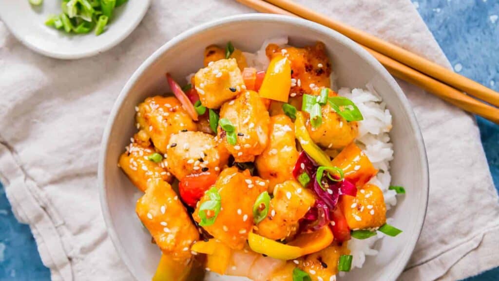 Chinese sweet and sour tofu stir fry in a bowl with chopsticks.