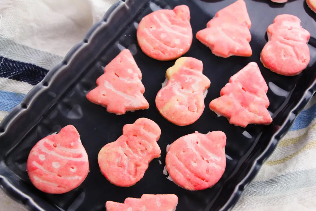 Black tray of shaped, glazed Christmas cookies.