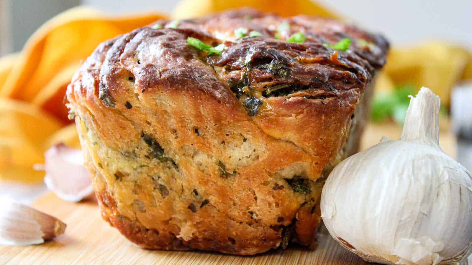 A loaf of bread with garlic and onions on a cutting board.