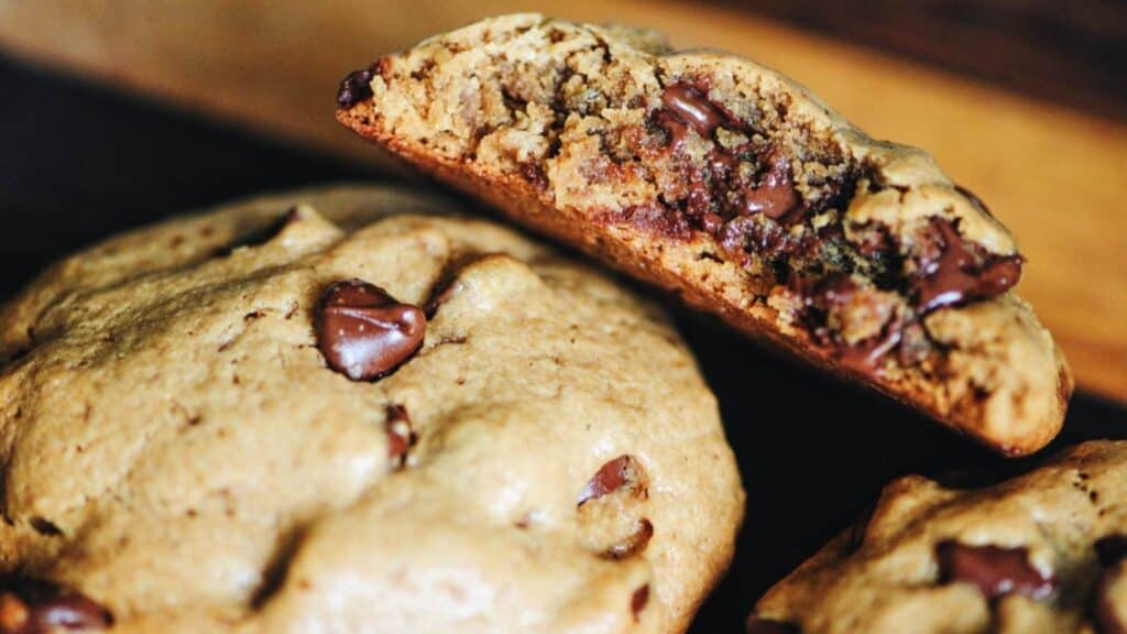 Two gluten-free chocolate chip cookies with a bite taken out of them.