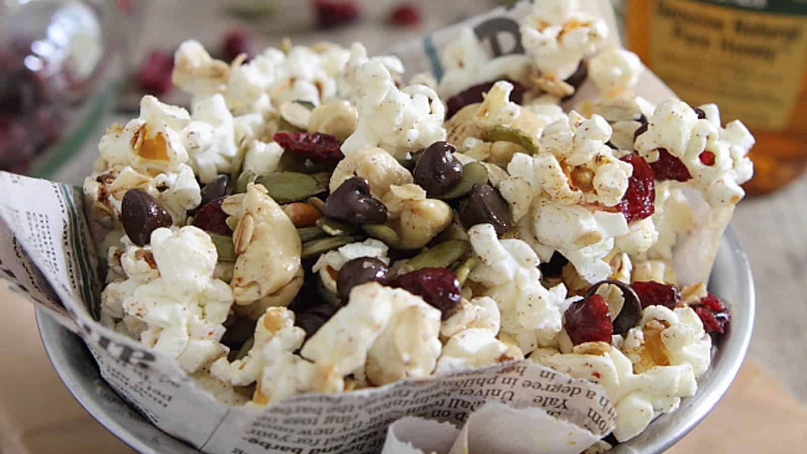 Trail mix popcorn in a bowl lined with newspaper.