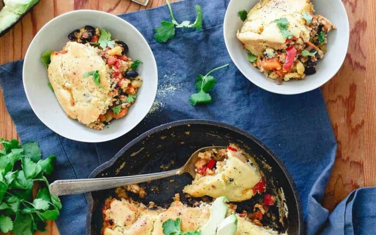 Turkey chili pie in a skillet on a blue tablecloth.