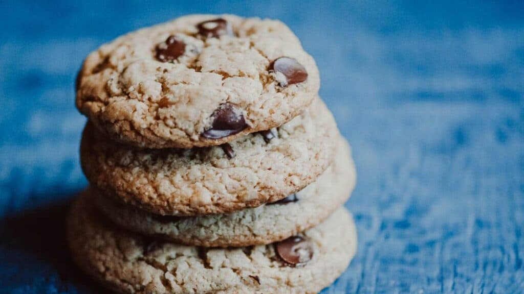 A stack of gluten-free chocolate chip cookies on a blue surface.