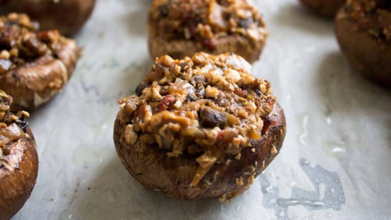 Some stuffed mushrooms are sitting on a baking sheet.