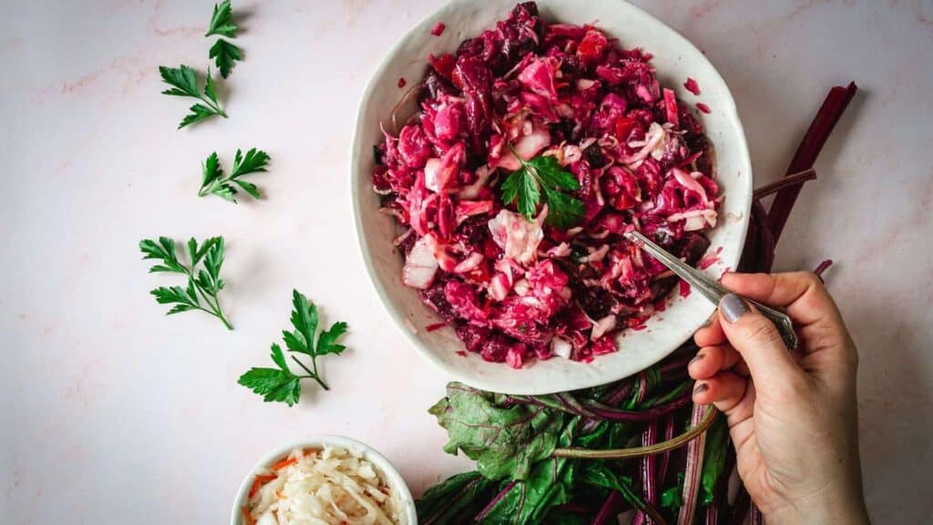 A person cutting up a bowl of red cabbage slaw.