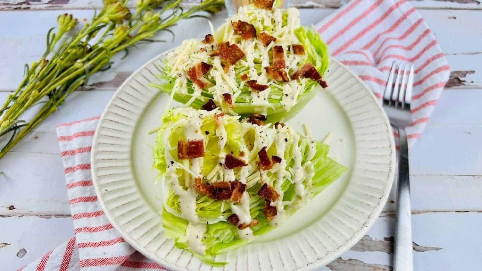 A white plate with two wedges of lettuce with bacon and dressing.