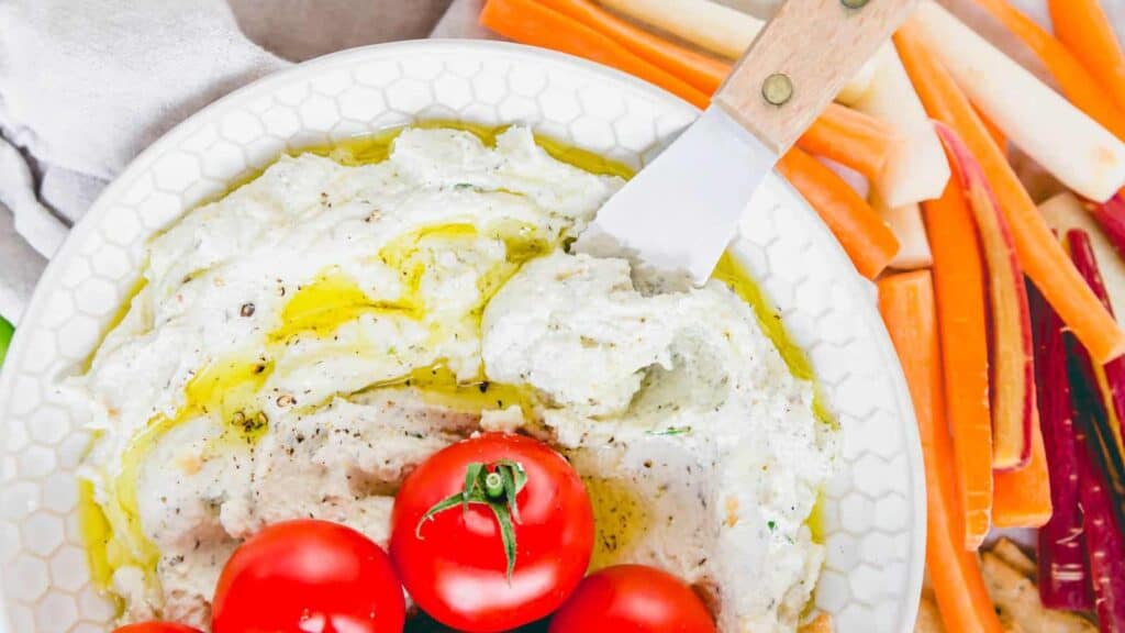 A bowl of whipped goat cheese with tomatoes and carrots.