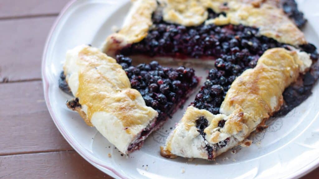 A fruit pie with blackberries on it is on a plate.