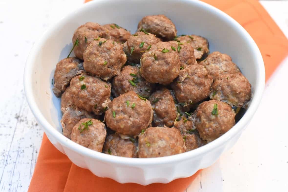 Meatballs in a white bowl on a napkin.