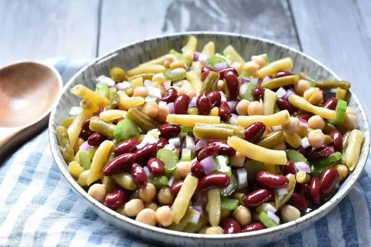 A bowl of bean and onion salad with a wooden spoon.