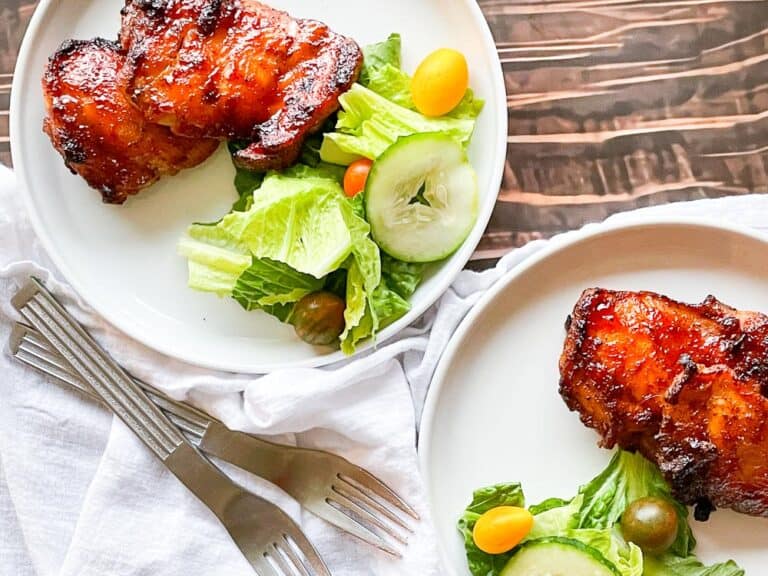 A plate of grilled chicken and salad on a wooden table.