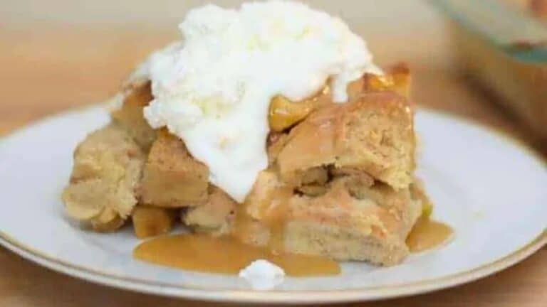 A plate of apple bread pudding topped with whipped cream.