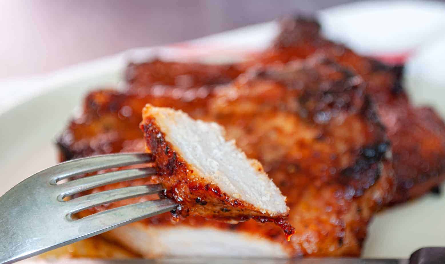 A bite of bbq pork chop on a fork.