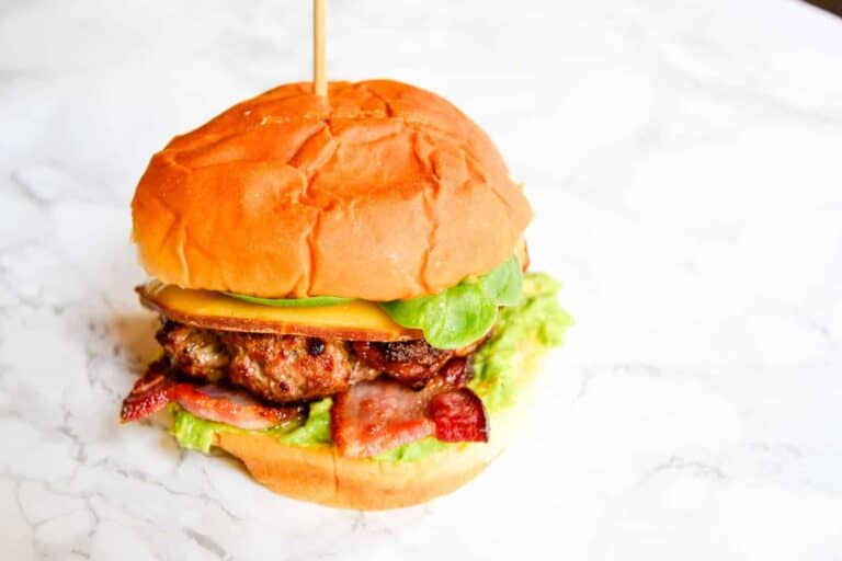 A burger with bacon, lettuce and avocado.