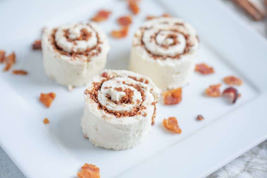 Three cinnamon roll cakes on a white plate.