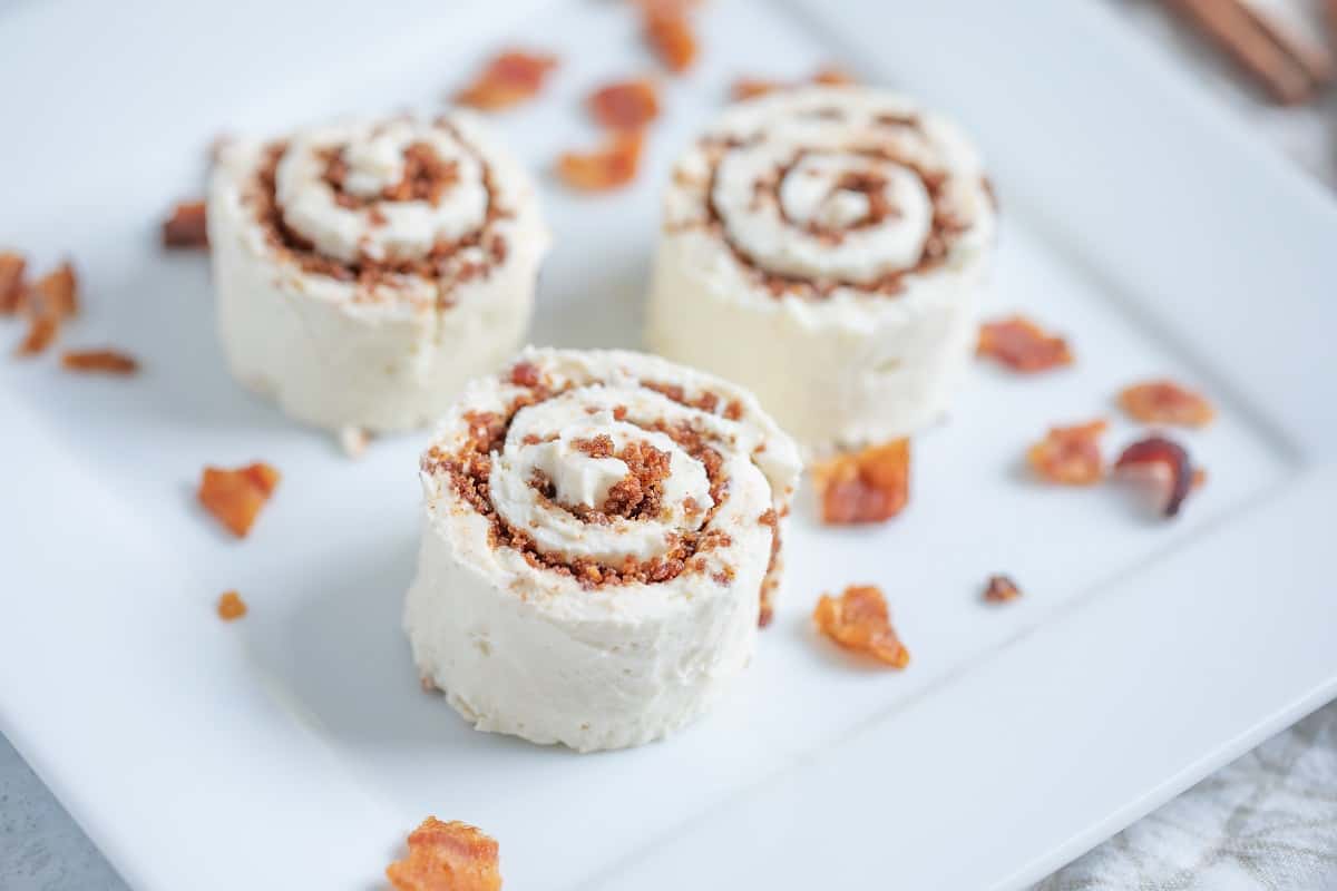 Three cinnamon roll cakes on a white plate.