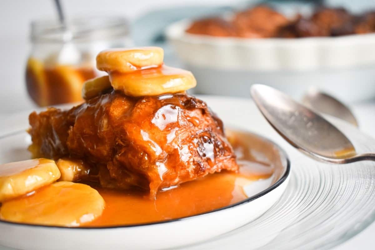 Serving of bananas foster croissant bread pudding with caramel drizzle.