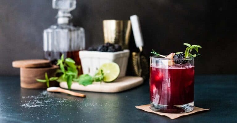 A cocktail with blackberries, mint and lime.