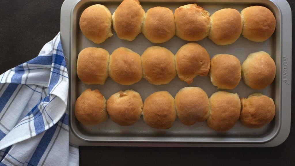 Rolls on a baking sheet next to a towel.