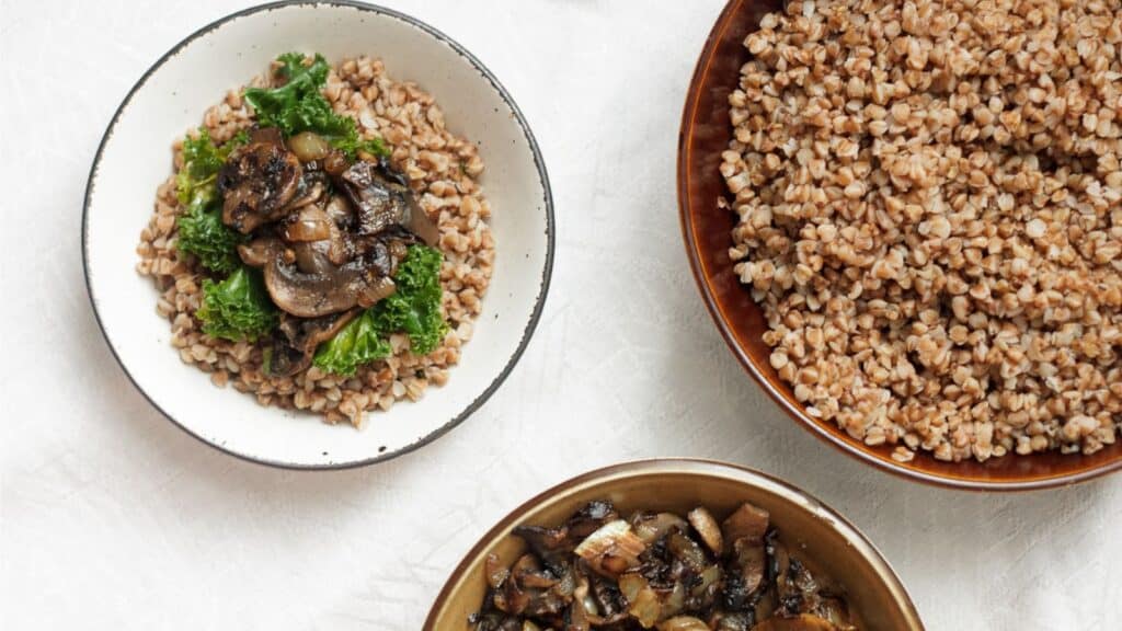 Three bowls of brown rice with mushrooms and greens.