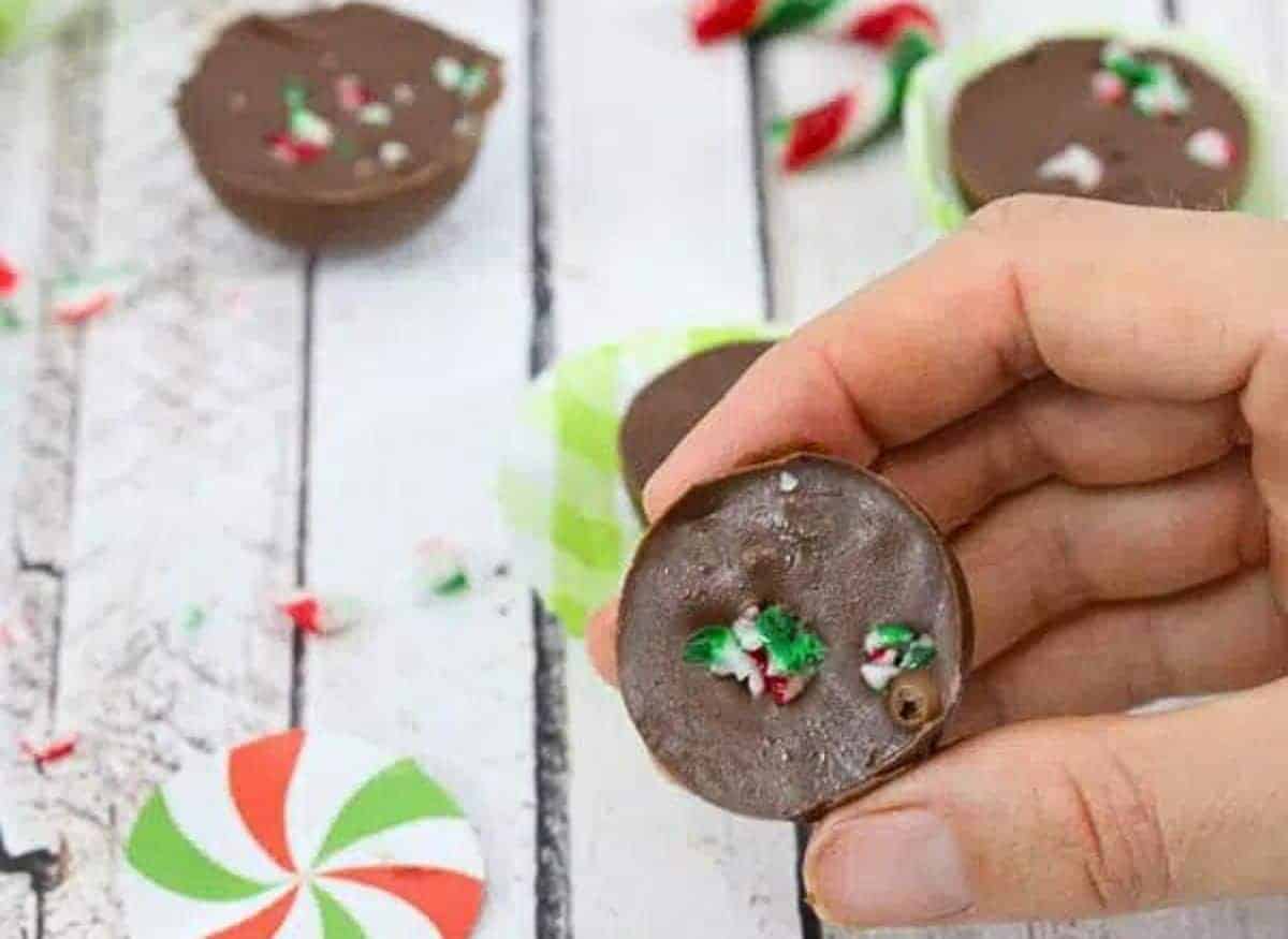 Two pieced of candycane fudge stacked the top with a bite out of it and more fudge and candy canes behind them.