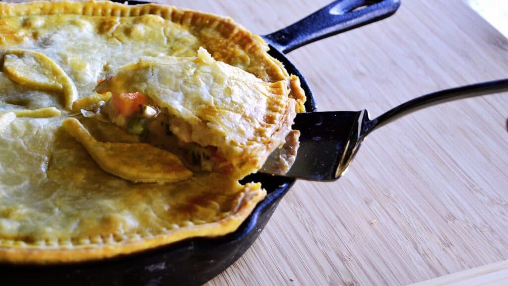 A person is taking a serving out of a chicken pot pie.