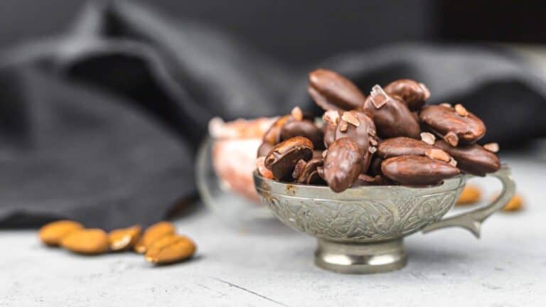 Chocolate covered almonds in a silver cup.