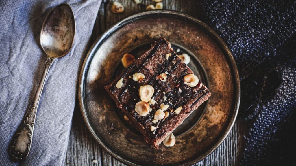 A piece of chocolate cake on a plate with a spoon.