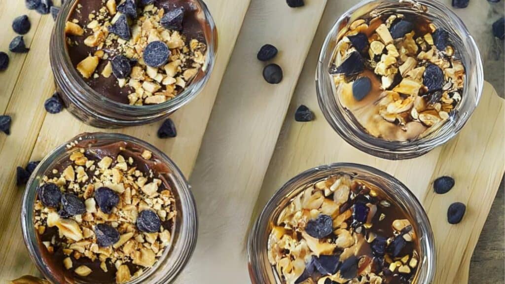 Four jars of chocolate granola on a wooden cutting board.