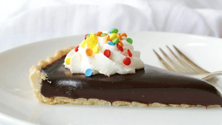 A slice of chocolate pie with whipped cream and sprinkles.