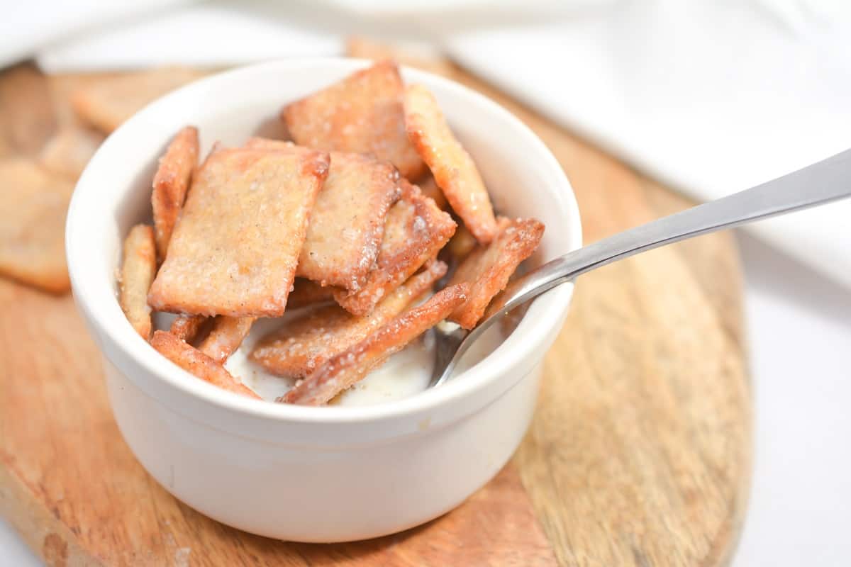 A white bowl filled with crackers and a spoon.