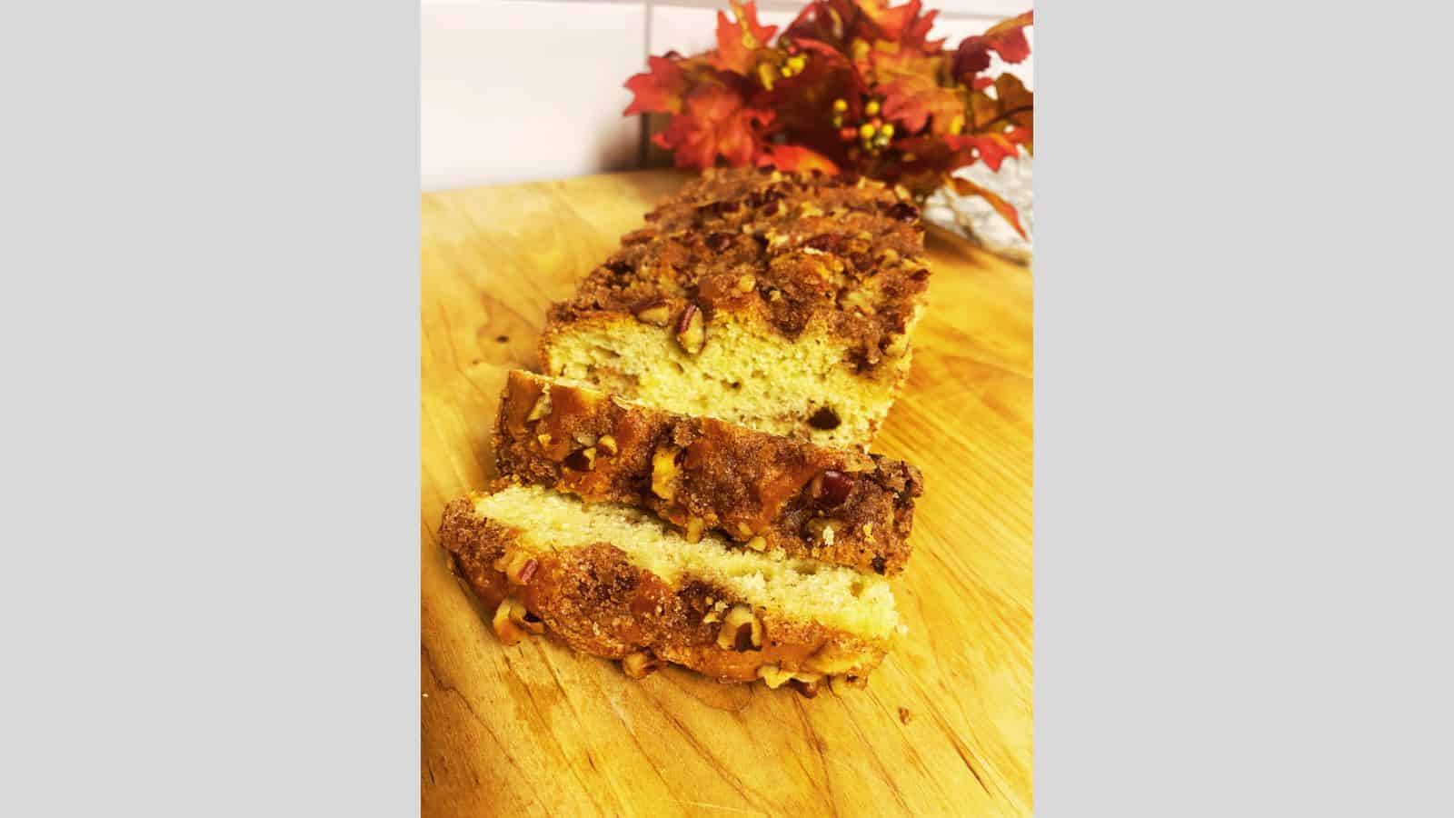 Loaf of cinnamon raisin bread with two slices falling forward on wooden board.