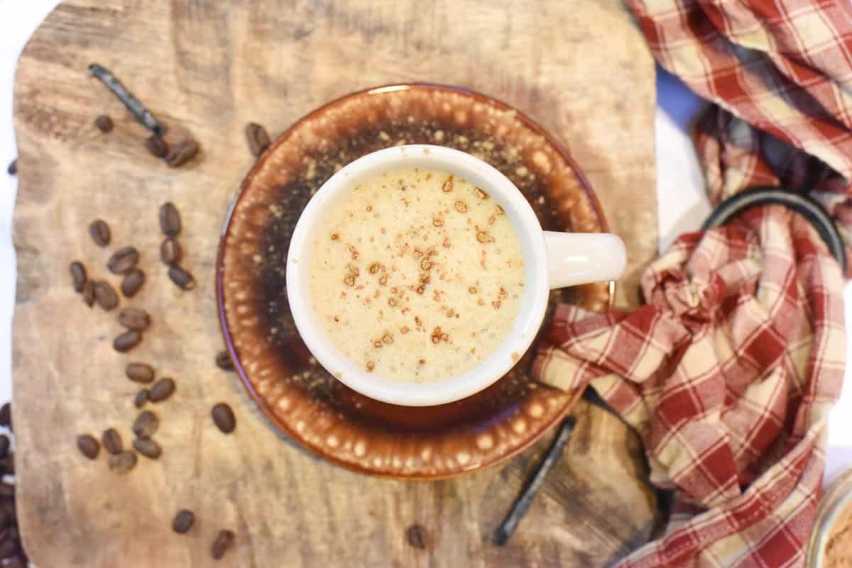 A cup of coffee on a wooden cutting board.