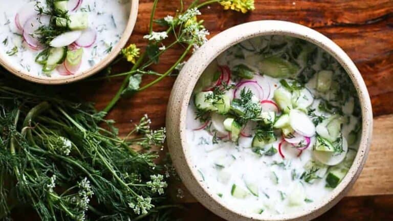 Two bowls of Eastern European soup with radishes and herbs.