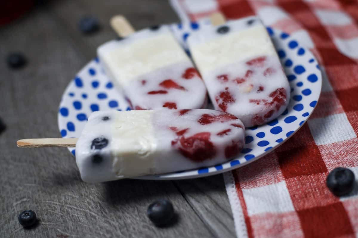 Popsicles with berries and blueberries on a plate.