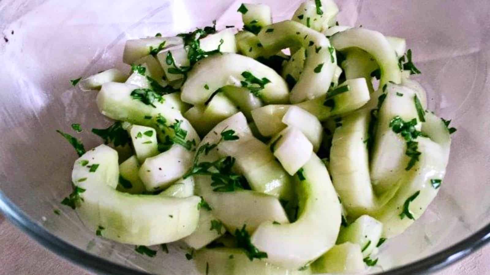 Image shows a close up of a summer Cucumber Salad in a clear bowl.