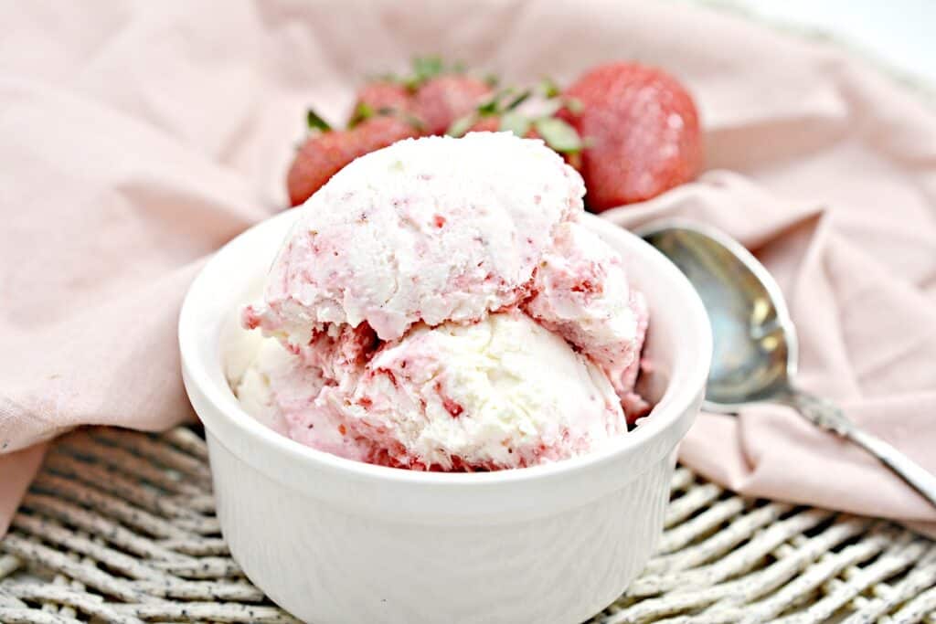 Strawberry ice cream in a white bowl.