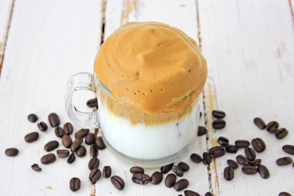 A cup of coffee ice cream surrounded by coffee beans.