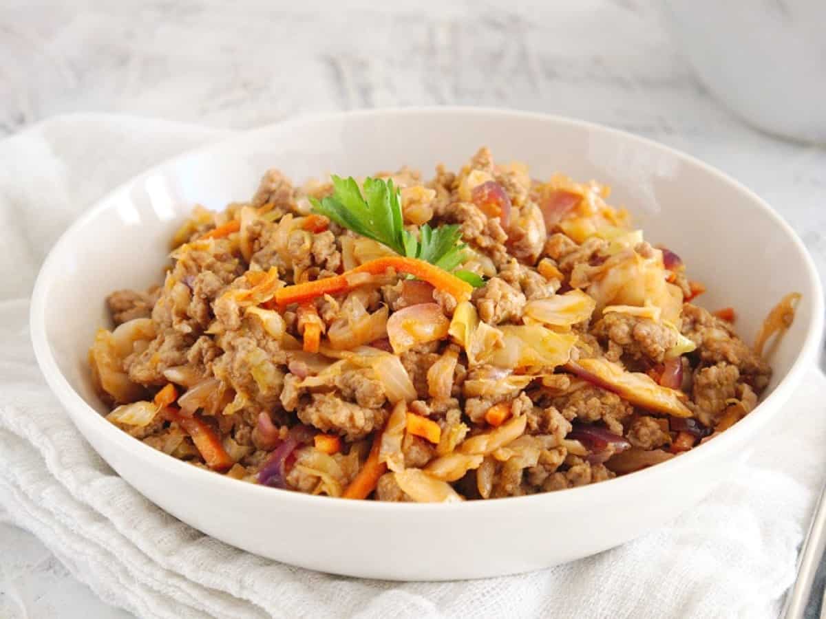 A bowl of meat and cabbage in a white bowl.