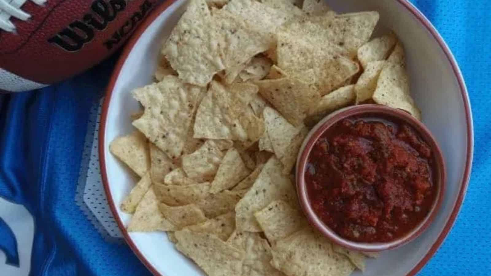 Bowl of chips with salsa and a football on a jersey.