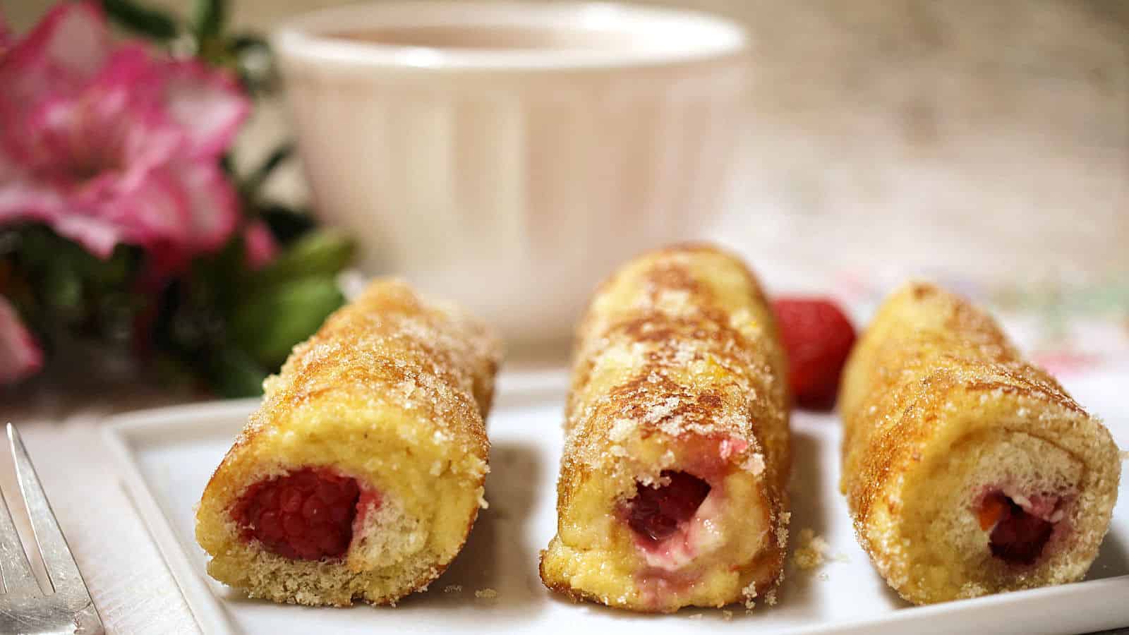 A white platter with raspberry French toast rolls.