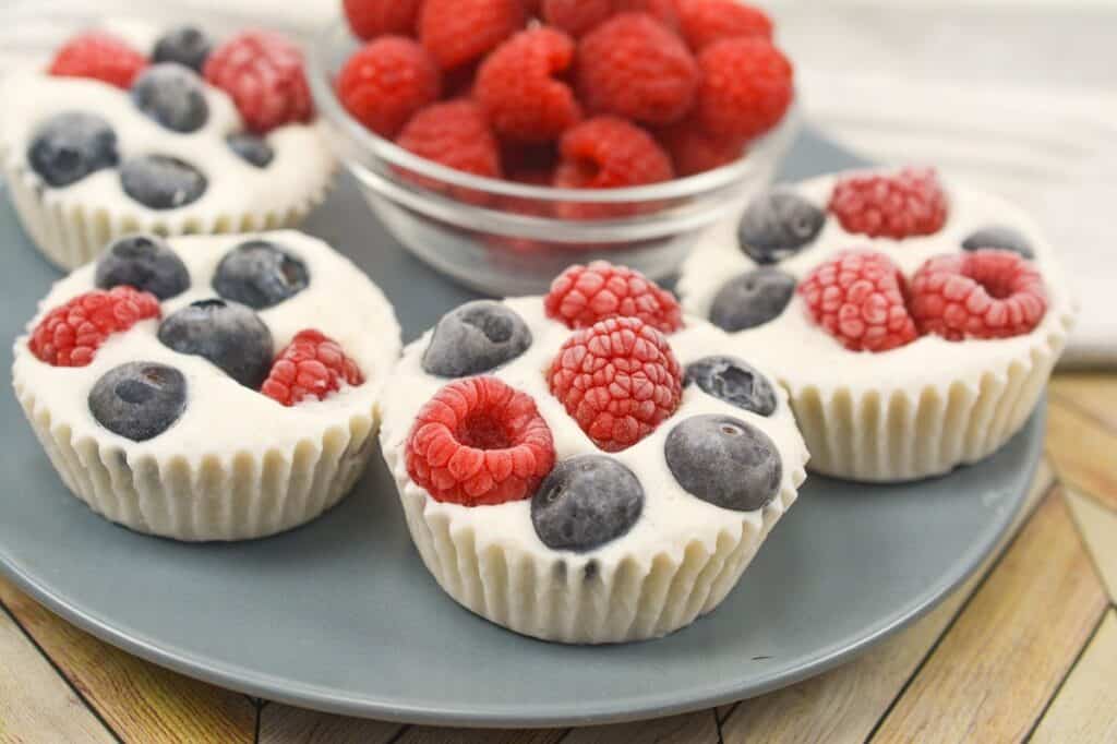 A plate of frozen yogurt with raspberries and blueberries on it.