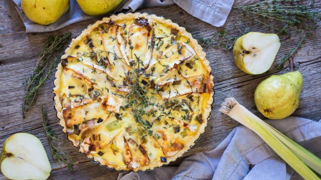 A pie with a few vegetables and a pear.