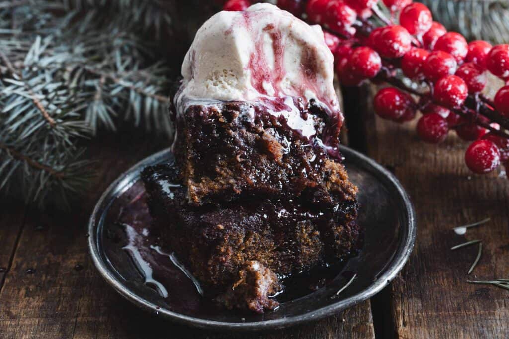 Classic Christmas pudding with ice cream and berries on a plate.