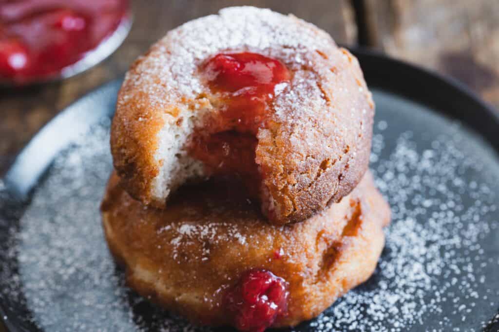 Classic cherry donuts with powdered sugar on a plate.