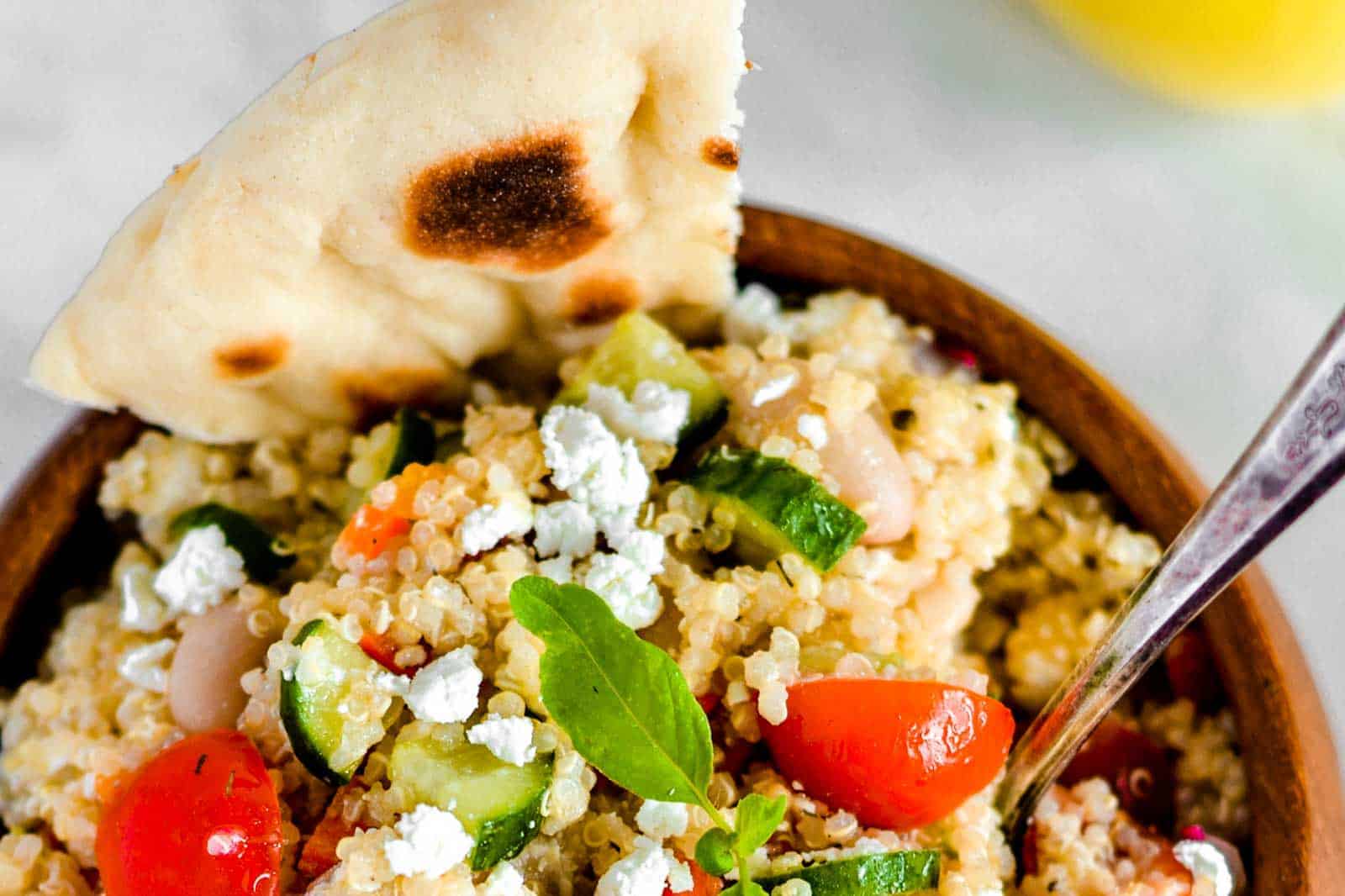 Quinoa salad in a brown bowl, garnished with pita bread.
