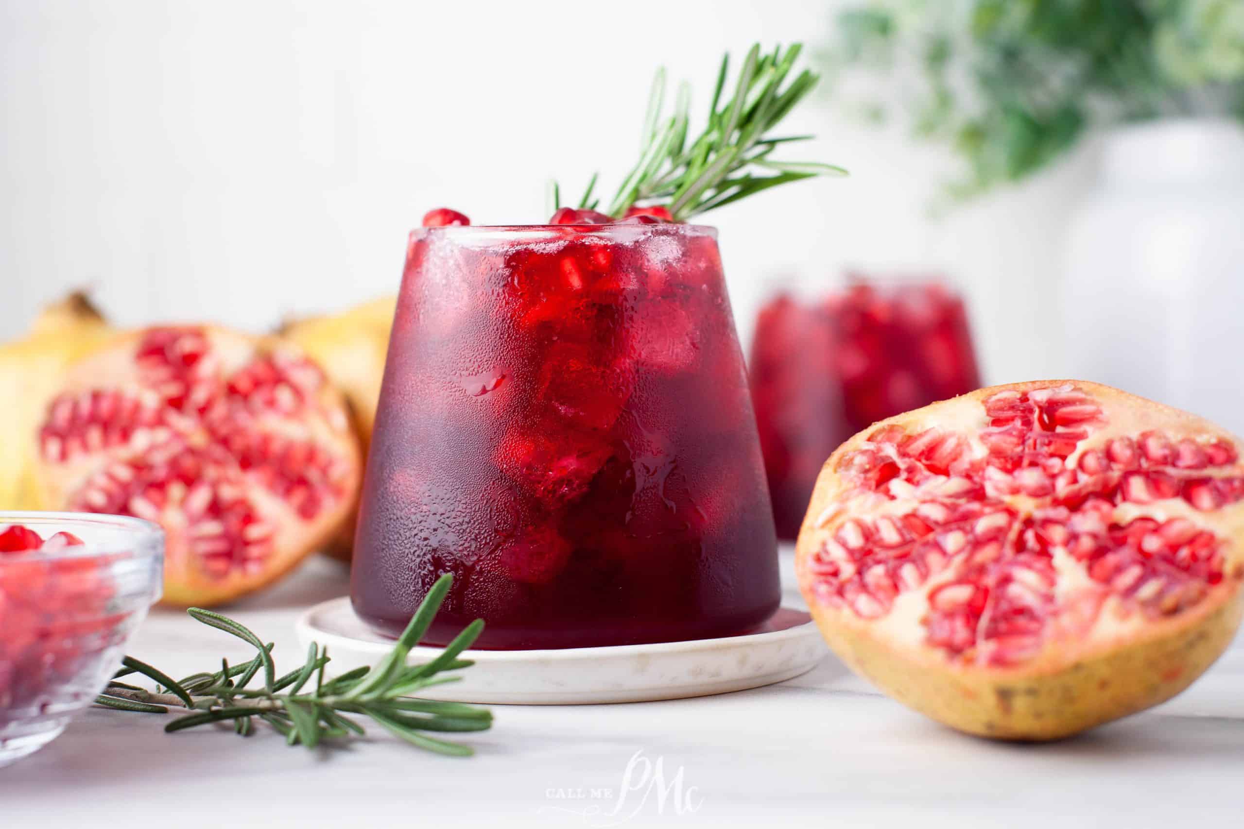 A glass of pomegranate juice with rosemary sprigs.