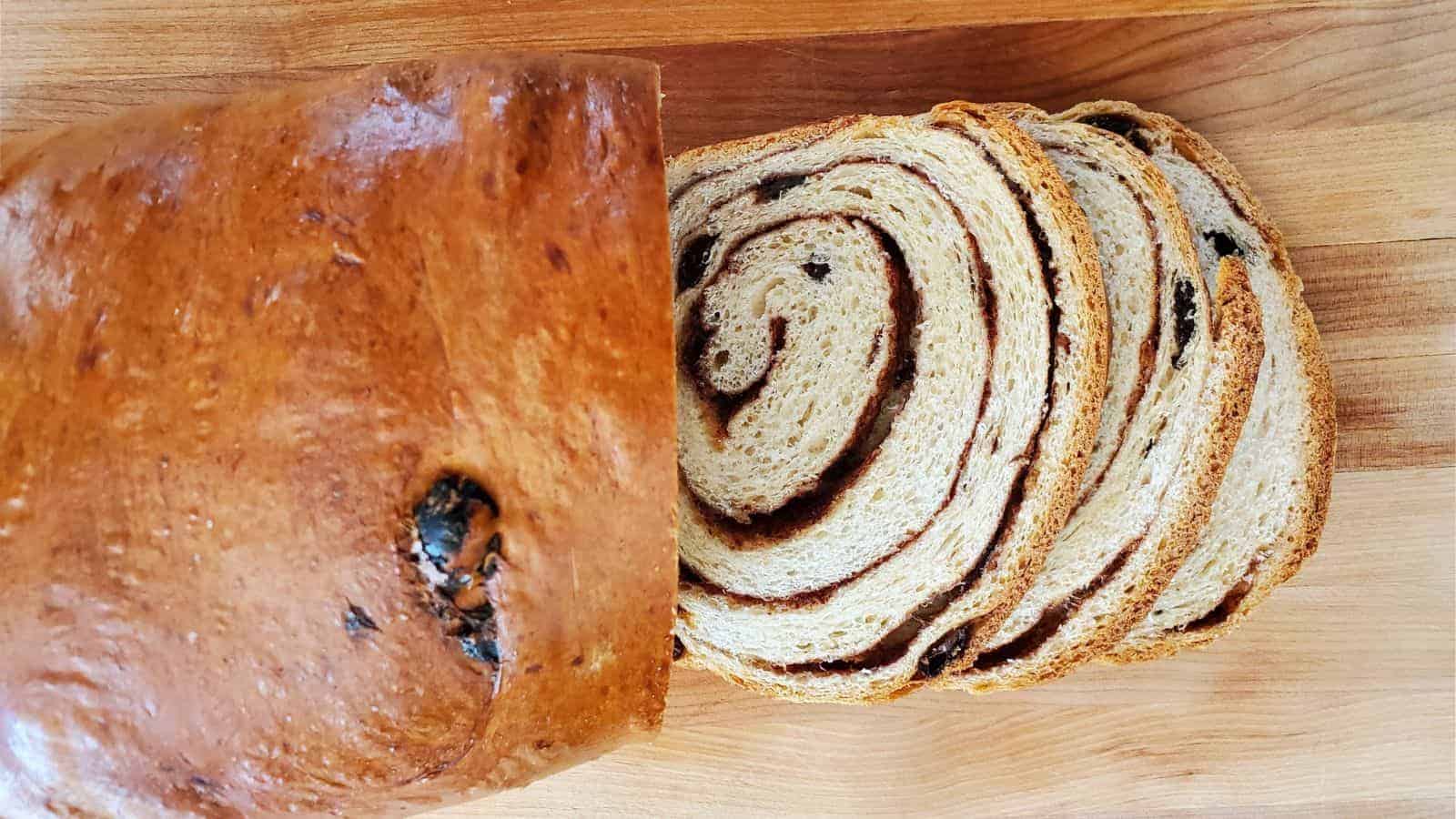 Image shows an overhead view of Cinnamon Raisin Bread with part of the loaf sliced.